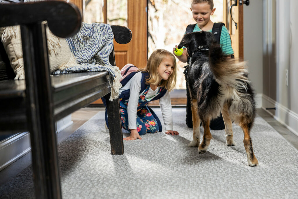 Kids plying with dog on carpet flooring | Shans Carpets And Fine Flooring Inc